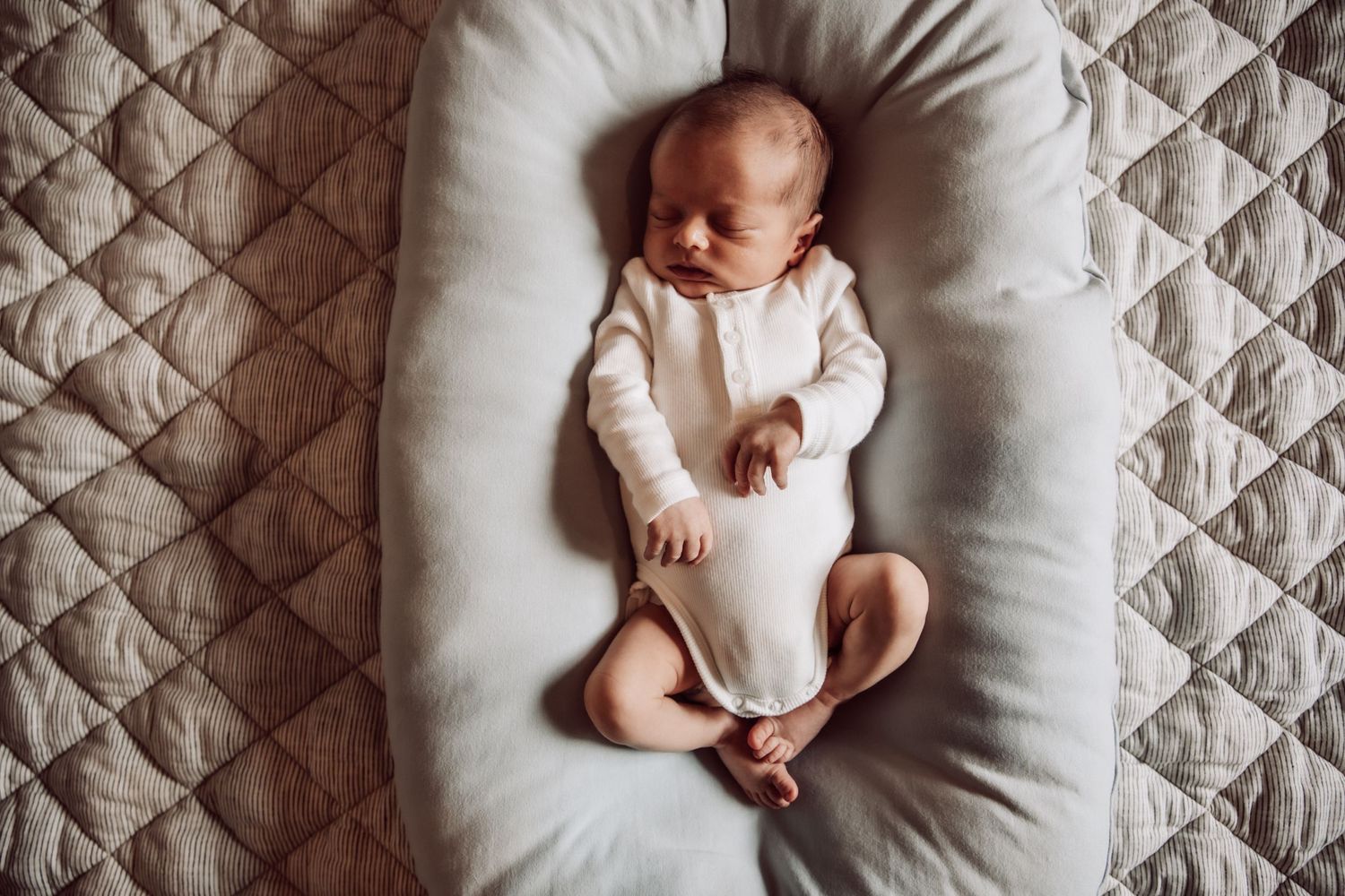 Series of tender newborn baby portraits taken from above on a quilted white mattress or pad.
