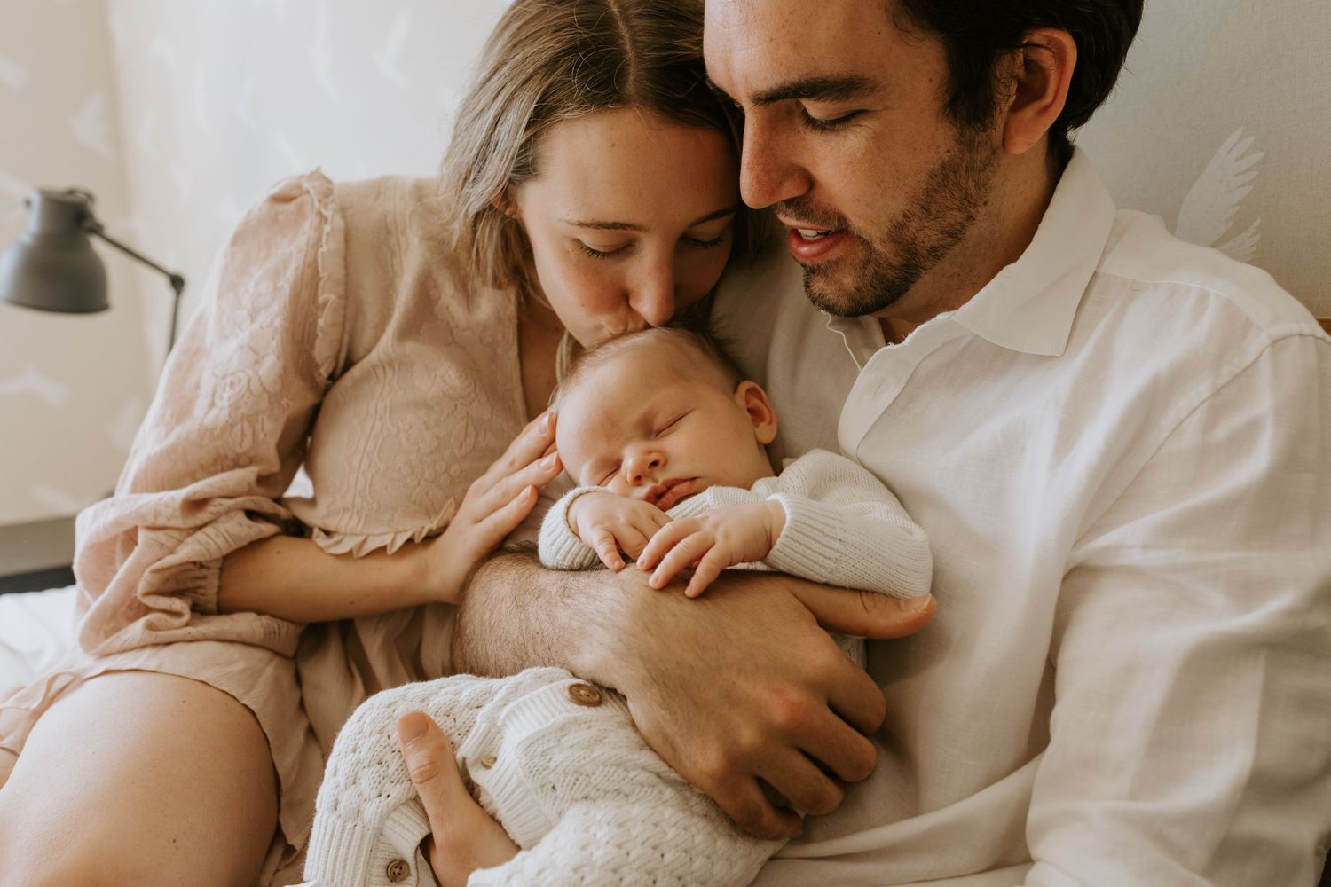Lifestyle family photography session on white bedding with soft neutral color palette.