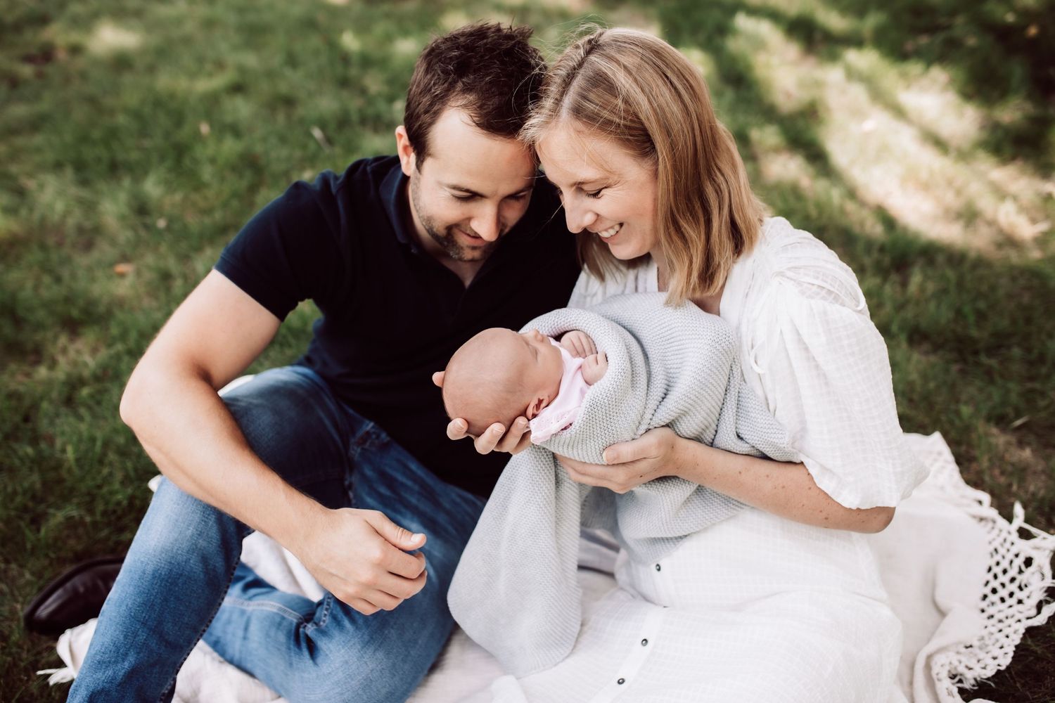 Family portrait session captured outdoors with natural golden lighting and green foliage.