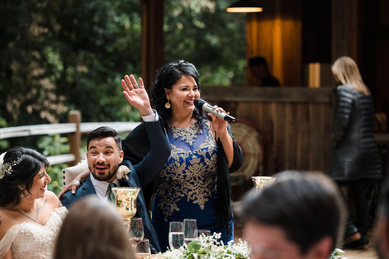 Outdoor wedding reception celebration among redwood trees with festive lighting.