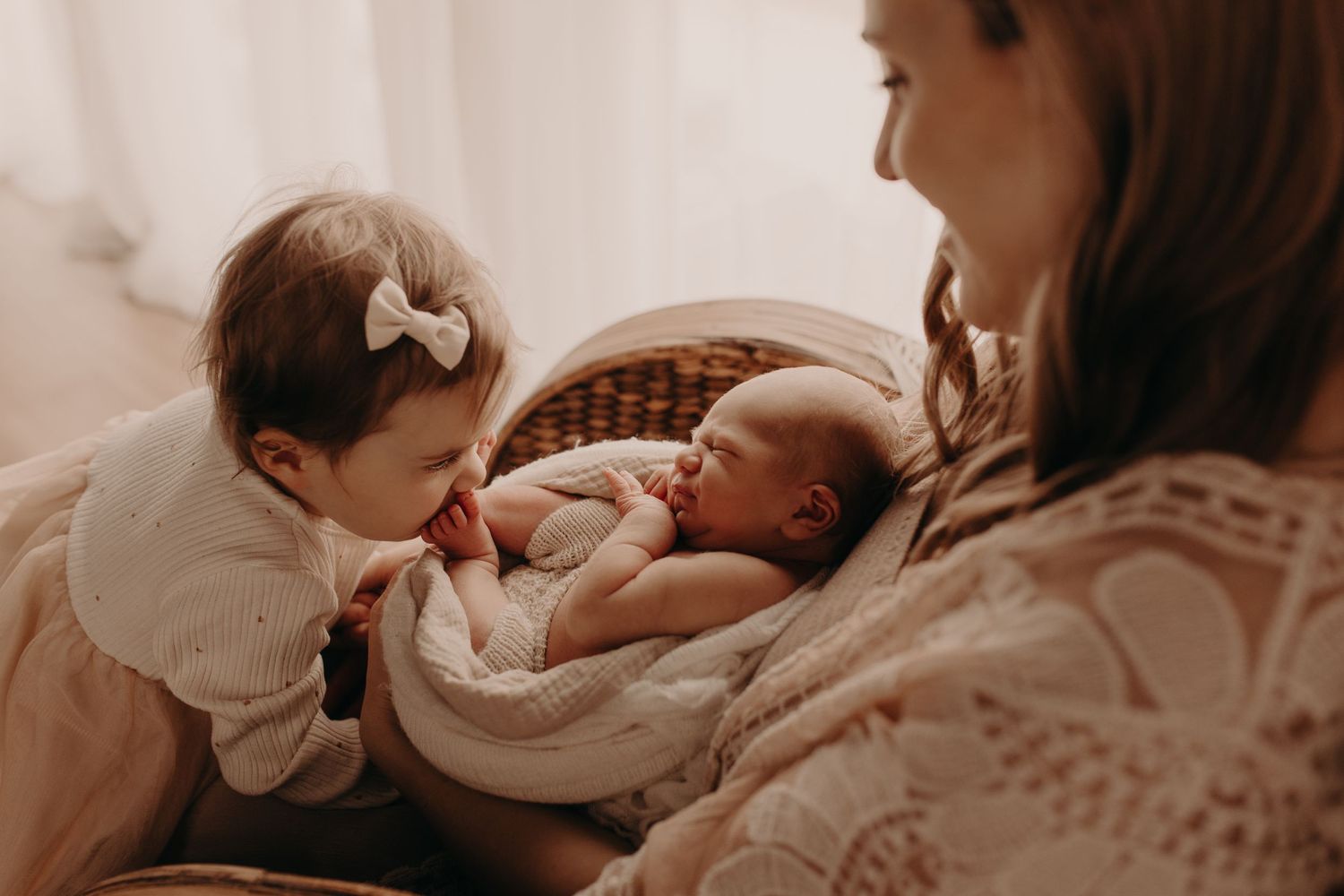 A heartwarming moment as siblings bond with a newborn baby swaddled in white.