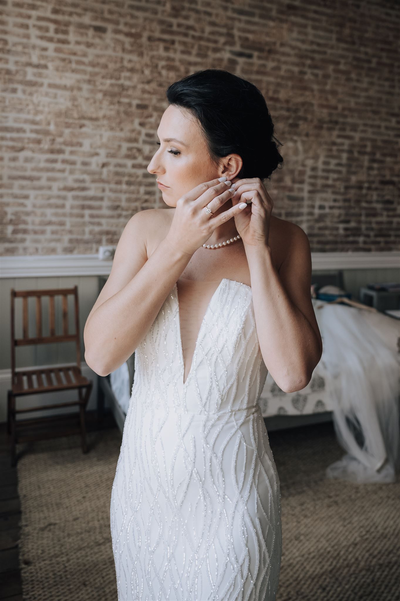 Elegant bridal preparation scene with pearl necklace against exposed brick wall background.