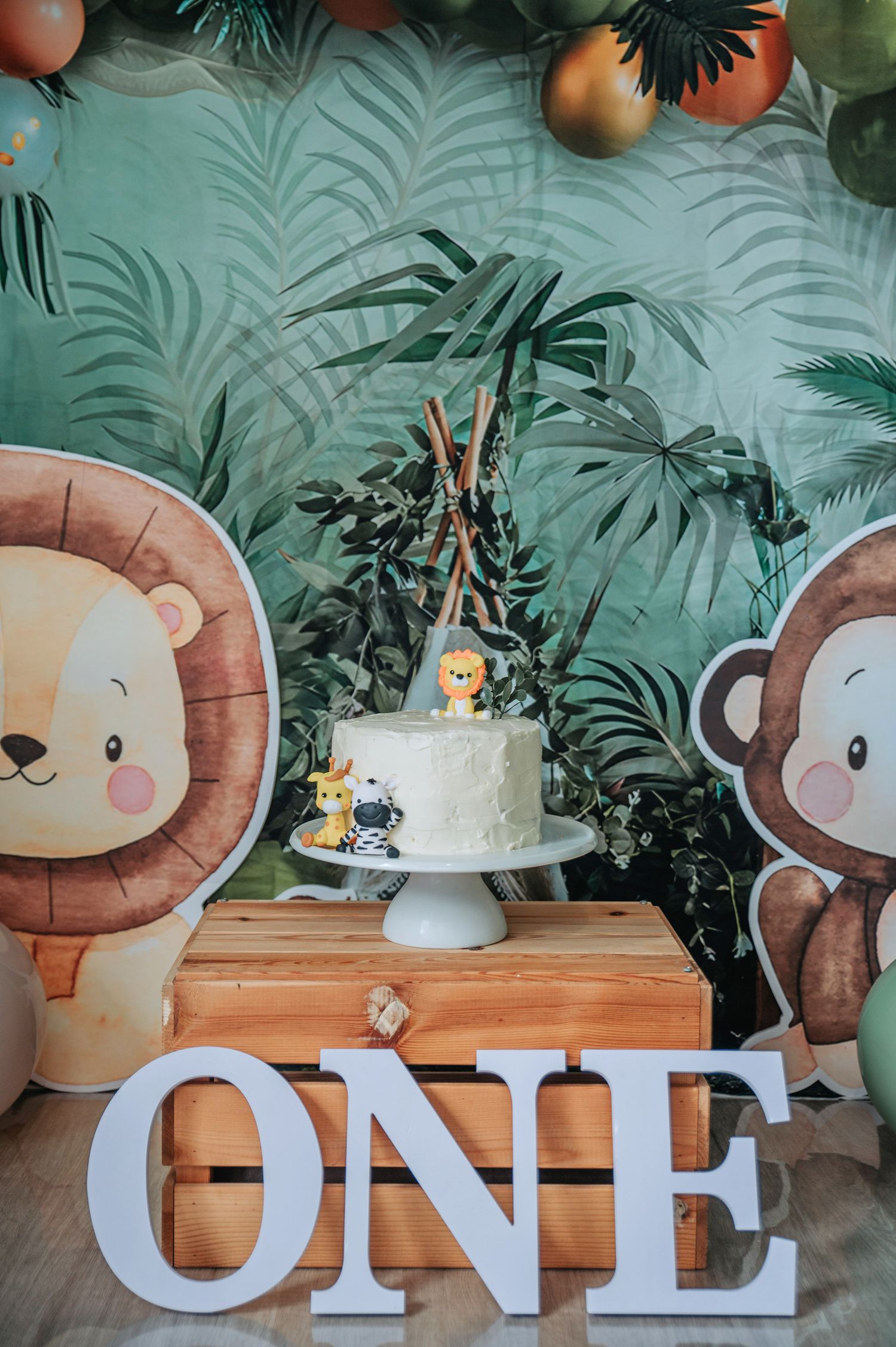 Safari themed first birthday party setup with cake and decorative lion and monkey cutouts.