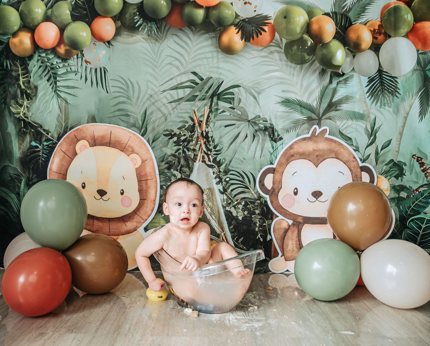 Jungle themed birthday setup with colorful balloons, safari animal cutouts and tropical leaf backdrop.