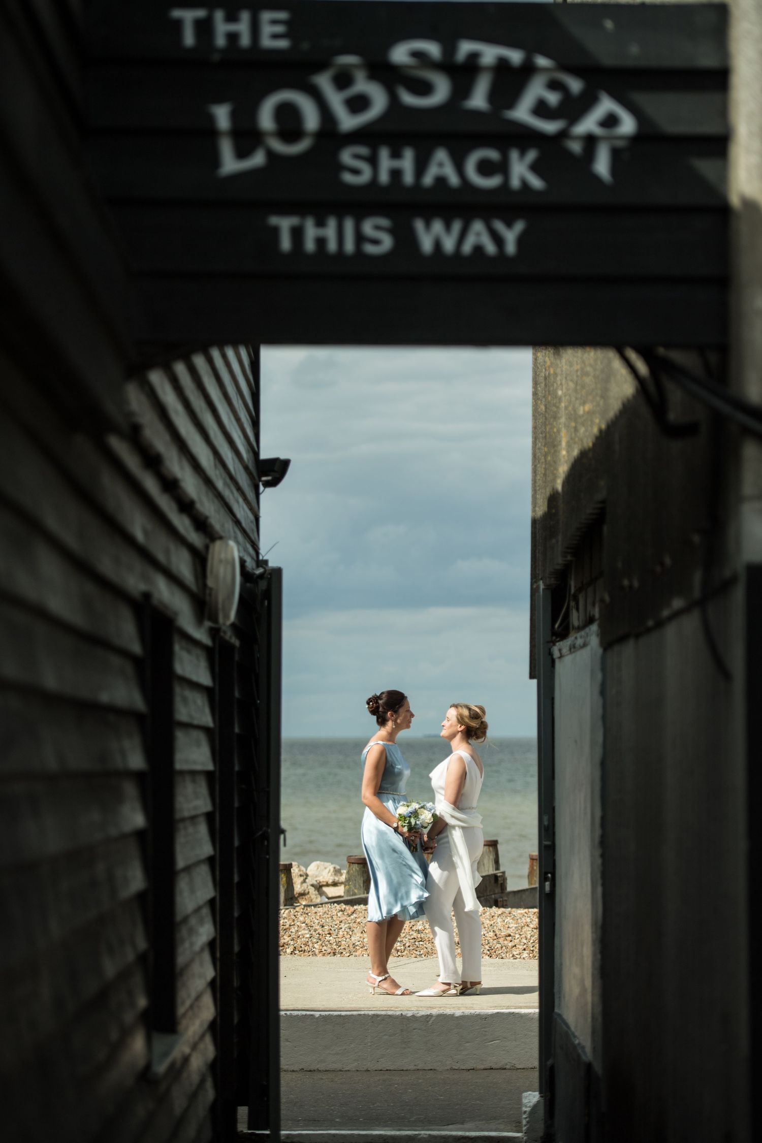 two brides share a moment on the beach next to the lobster shack in whitstable