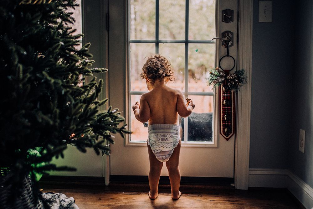 child in diaper by window
