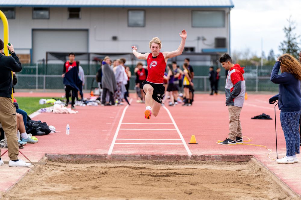 Athlete demonstrating explosive power and agility during a long jump in track and field competition