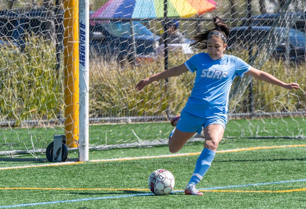 Young lady displaying skill and precision as she kicks the soccer ball with determination during a spirited game