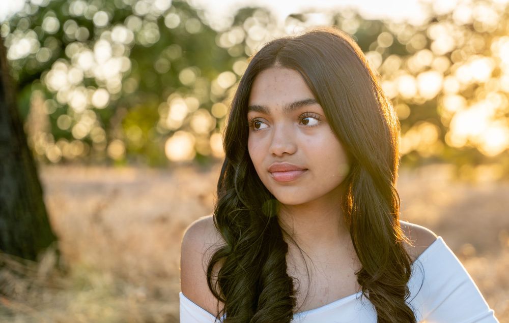 Young lady captivated by the serene beauty of the setting sun, gazing thoughtfully into the distance.
