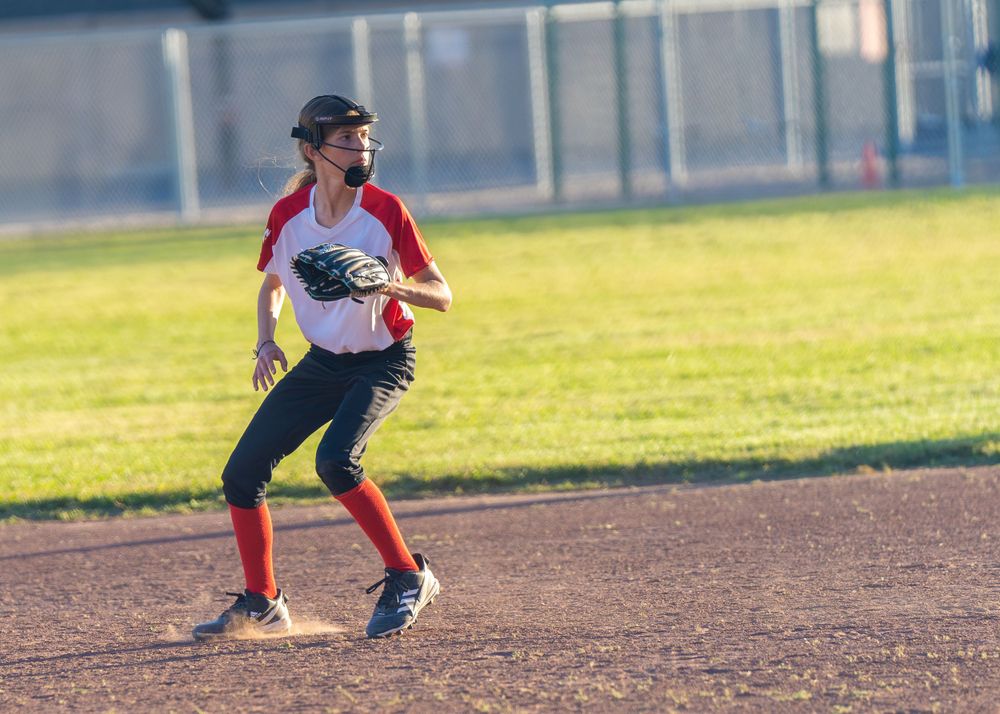 oung lady skillfully fielding a softball with precision and agility during an intense game