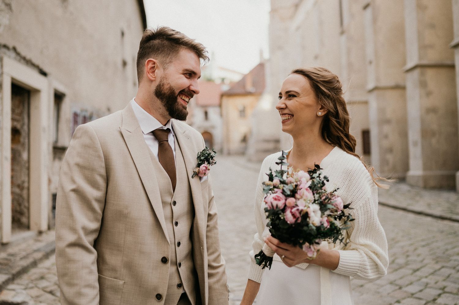 Joyful wedding moment captured on cobblestone street with vintage architecture.