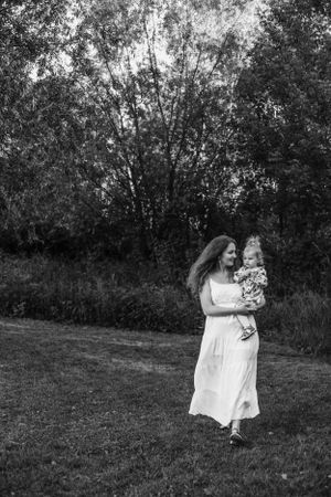 Black and white portrait of parent and child walking through nature landscape.