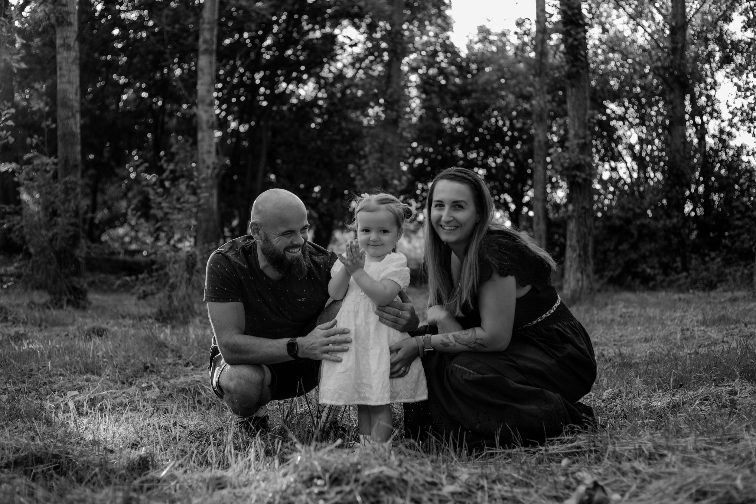 A family poses together on grass during an outdoor photo session at sunset.