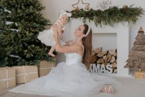 Joyful Christmas portrait in front of decorated tree and fireplace with wrapped presents.