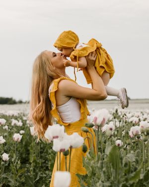 Sweet moment captured in poppy field with yellow clothing and soft sunset lighting.