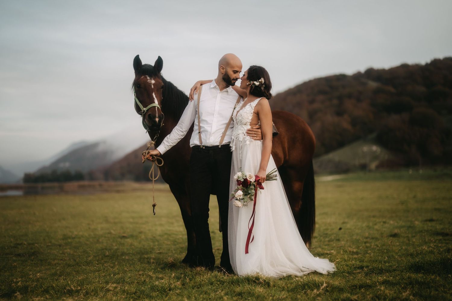 Wedding couple poses with their horse in a rustic mountain setting.