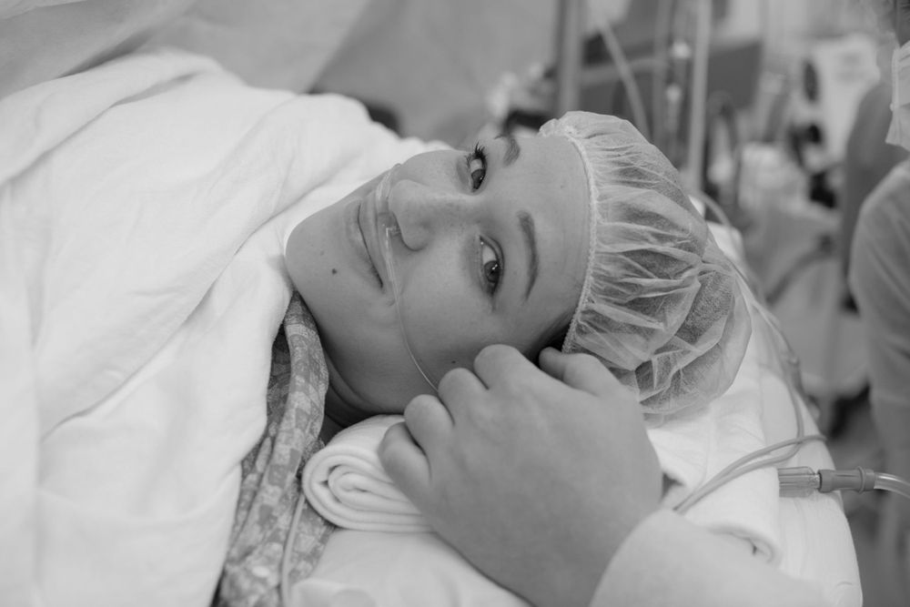 Patient resting on hospital bed wearing surgical cap.