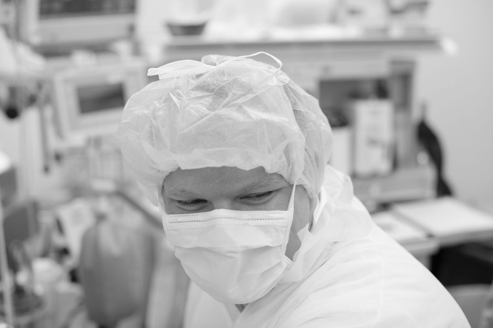 Medical team in protective gear performing surgery in operating room.