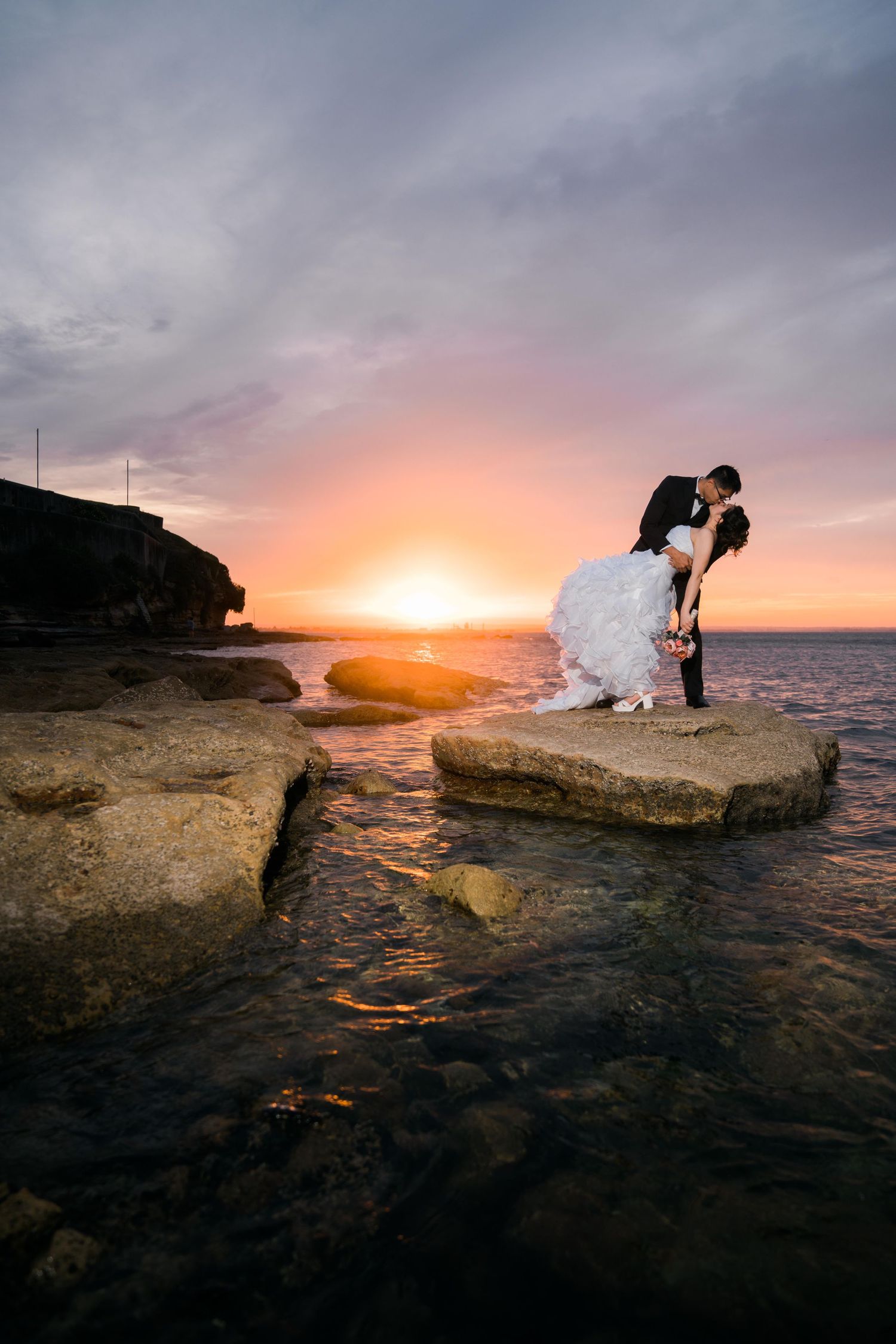 Bride and groom show off their dipping kiss at sunset at La Perouse Beach