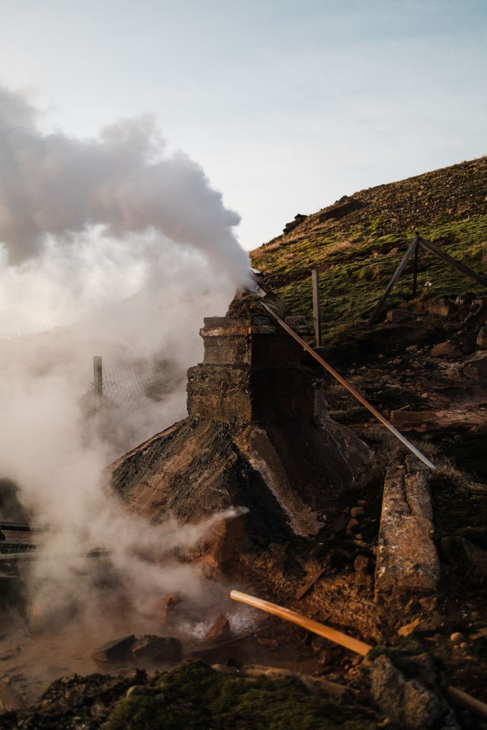 Steam rises from ancient stone structures on rugged mountainside.