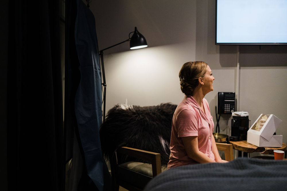 Person sits at desk illuminated by desk lamp in dark room during work session.