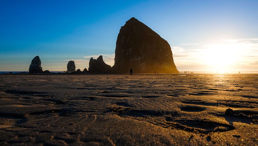 Haystack Rock silhouetted against a sunset sky on Cannon Beach, Oregon.