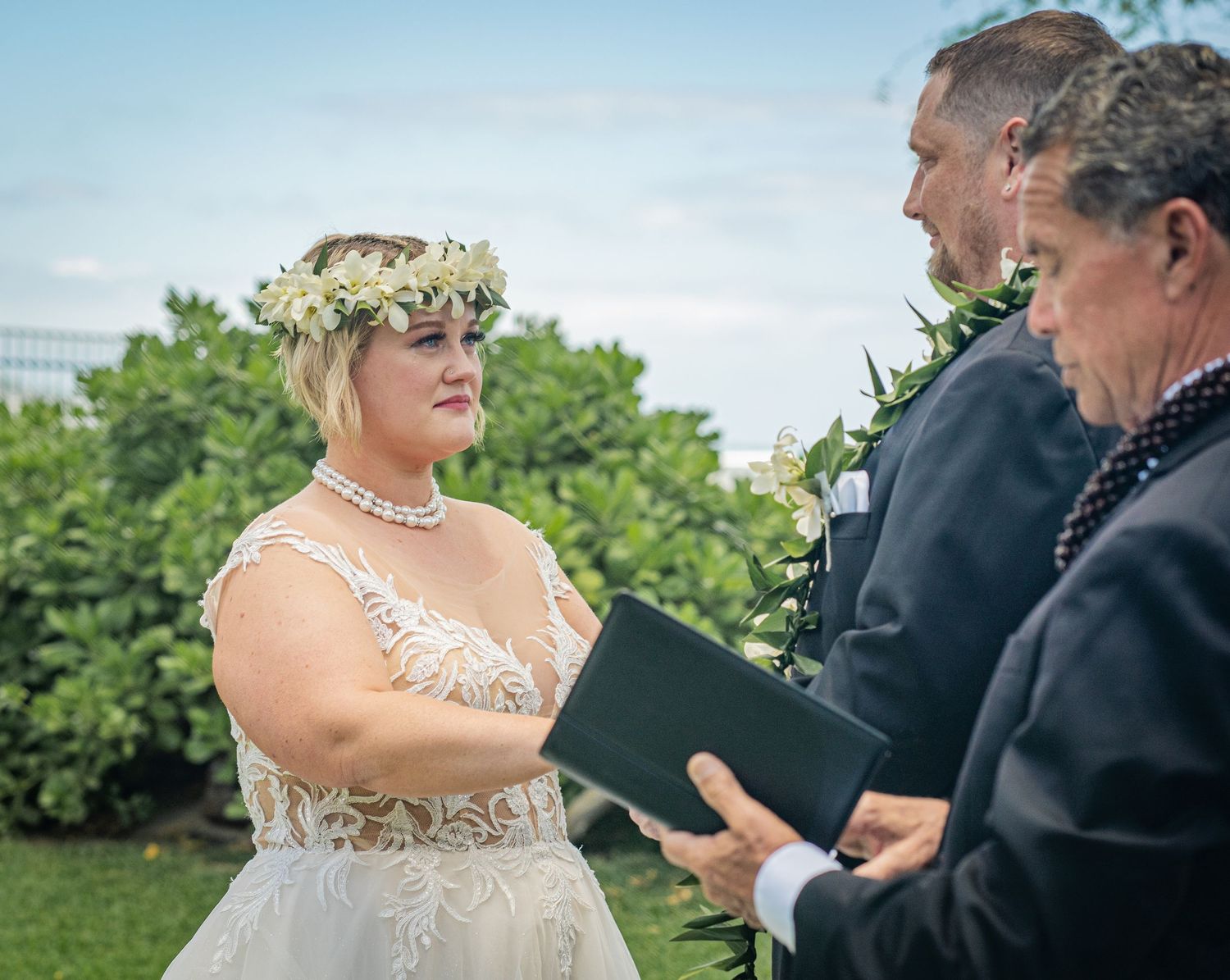 Outdoor wedding ceremony with floral crown and officiant performing the service.