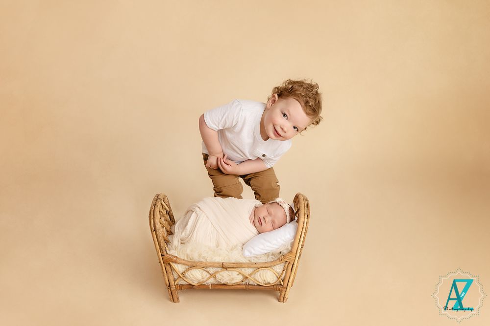 Vintage style nursery scene with wicker doll bed against beige backdrop.