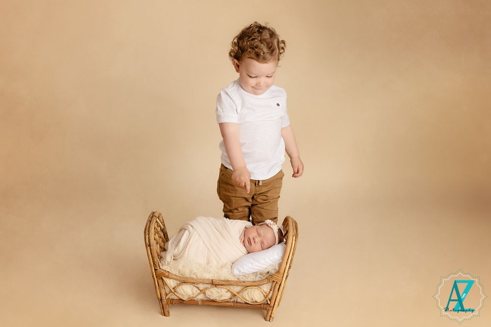 Studio portrait setup with wicker furniture and neutral beige background.
