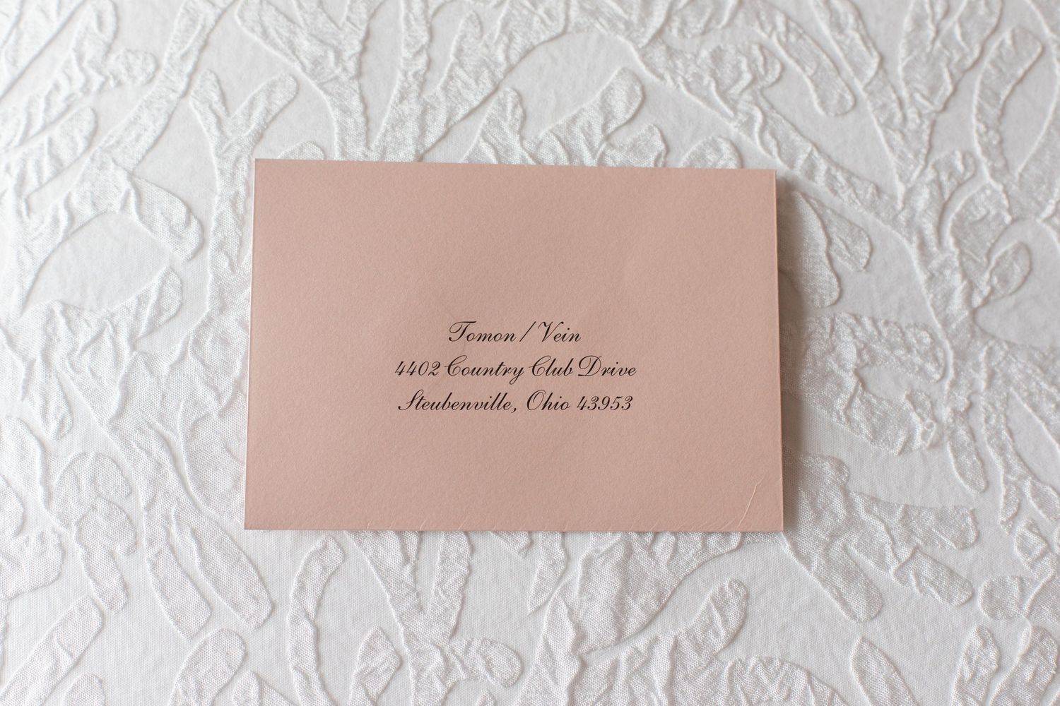 Wedding invitation envelopes and cards arranged on white textured background.