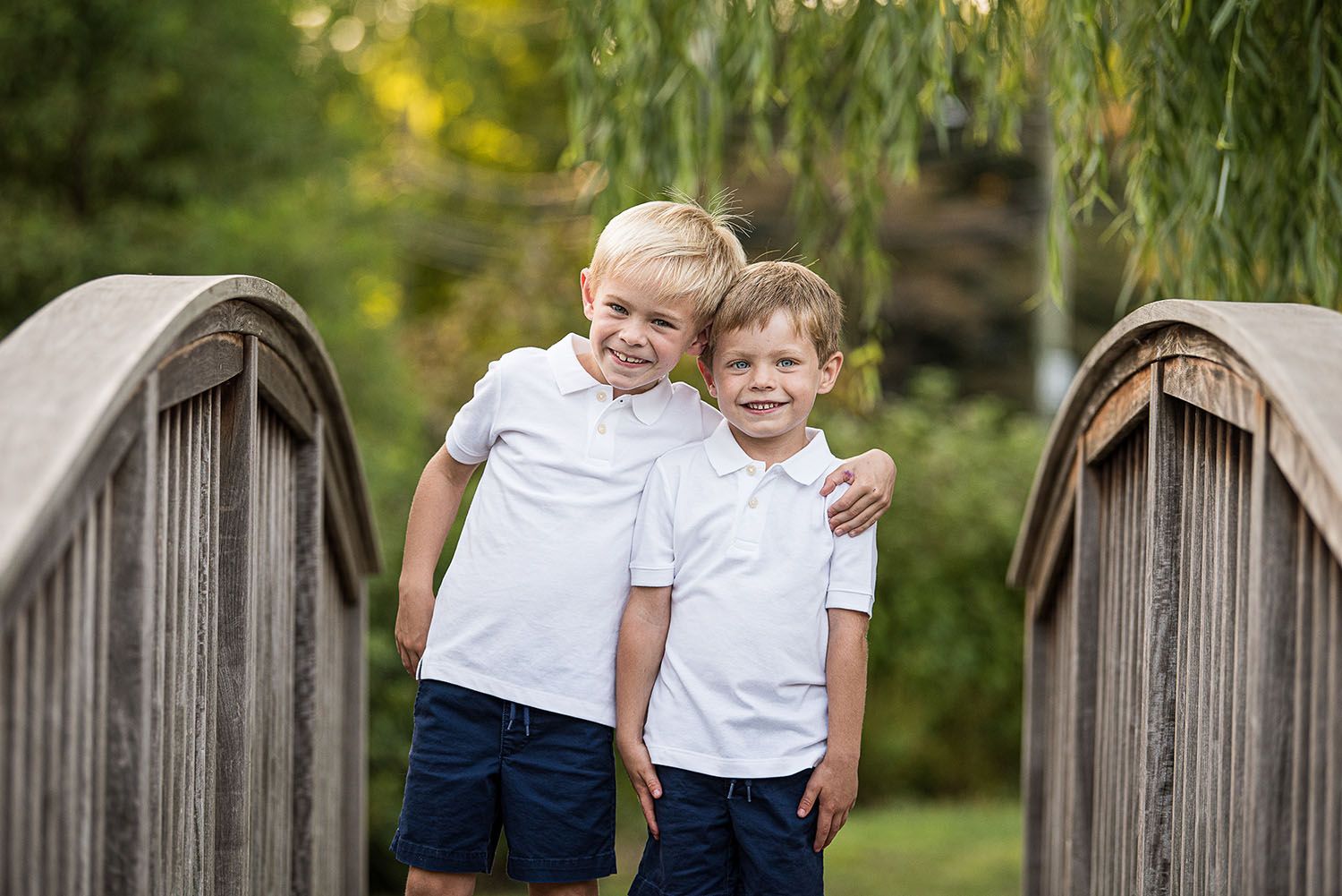 Brothers with arms around each other with greenery background and willow tree
