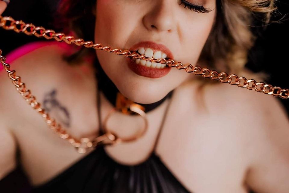 Artistic close-up of gold chain necklace against dark background.