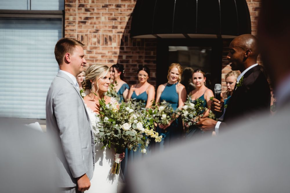 Wedding ceremony moment with bridesmaids in blue dresses and floral bouquets.