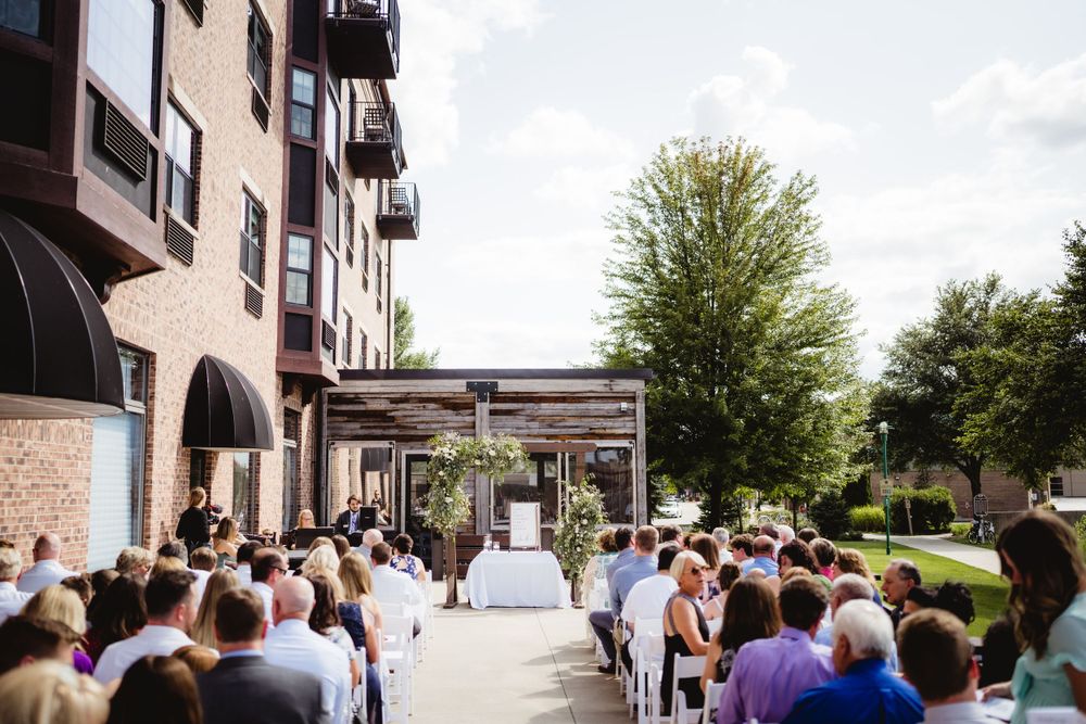 Outdoor wedding ceremony setup with rows of white chairs and floral arch.