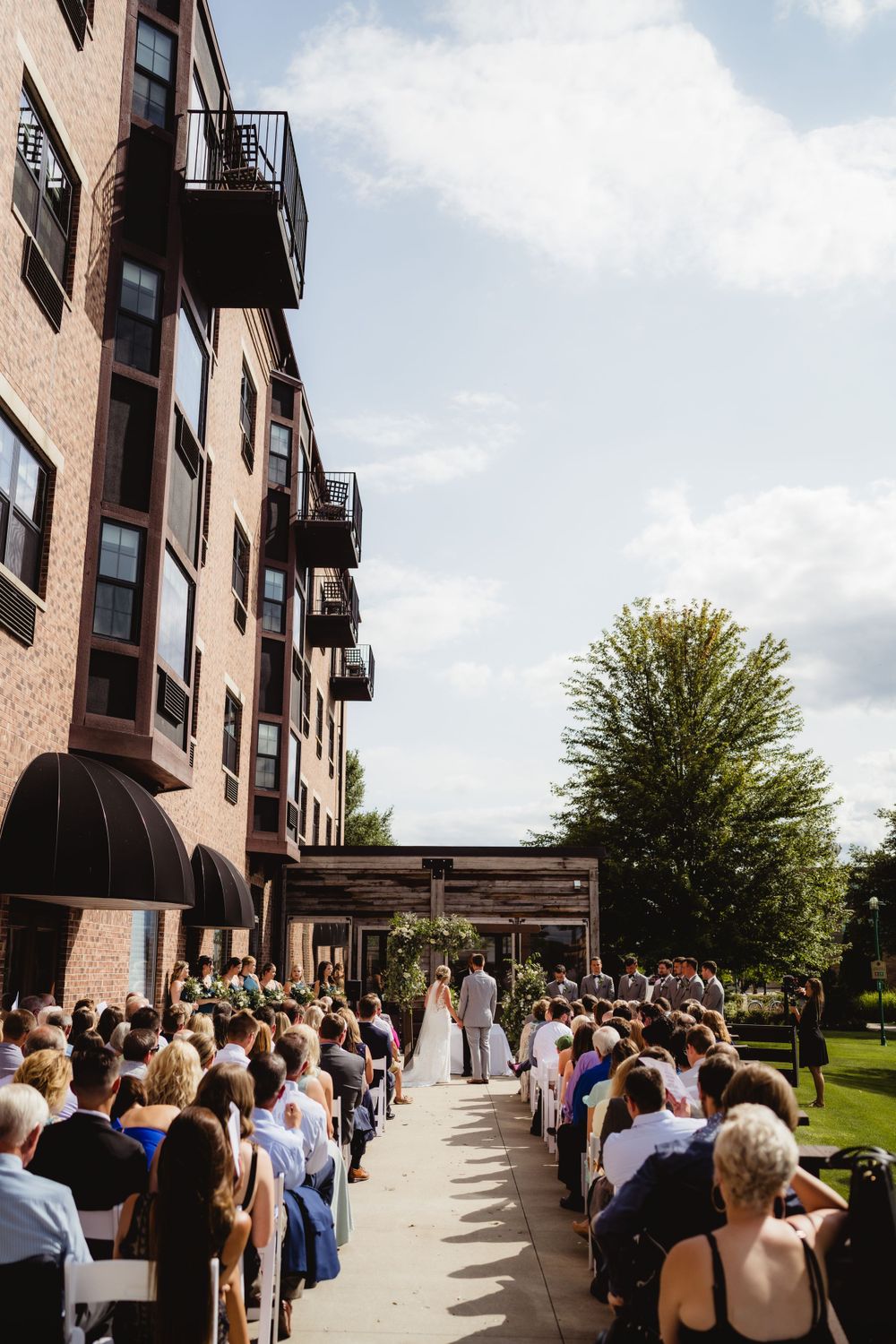 Aerial view of outdoor wedding ceremony with guests seated in rows at urban venue.