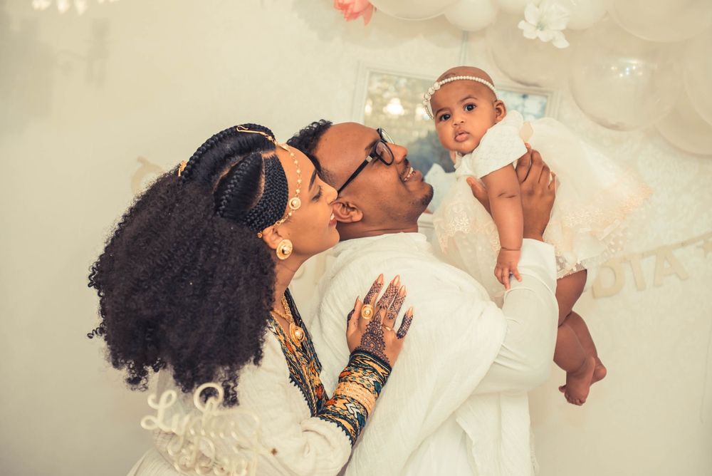Tender family moment captured against white background with floating floral decorations.