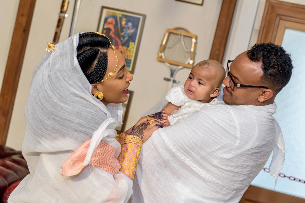 Intimate family gathering in traditional white attire captured in home setting.