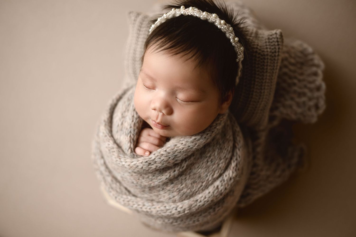 Artistic newborn portraits featuring soft gray wrapping and delicate headband.