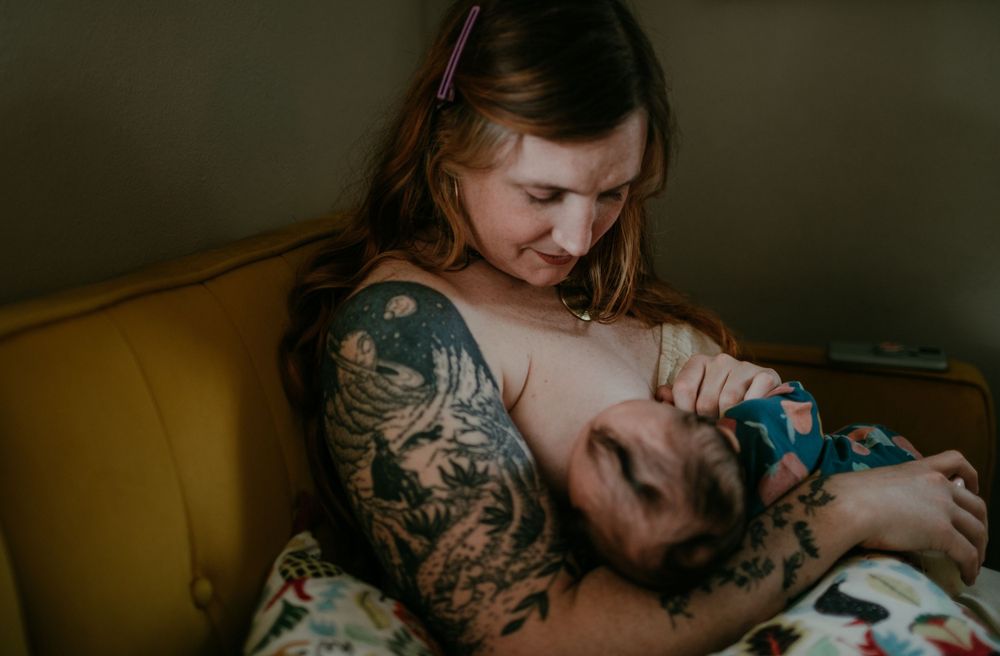 trans mother chestfeeds infant during in-home newborn session portland oregon newborn photographer