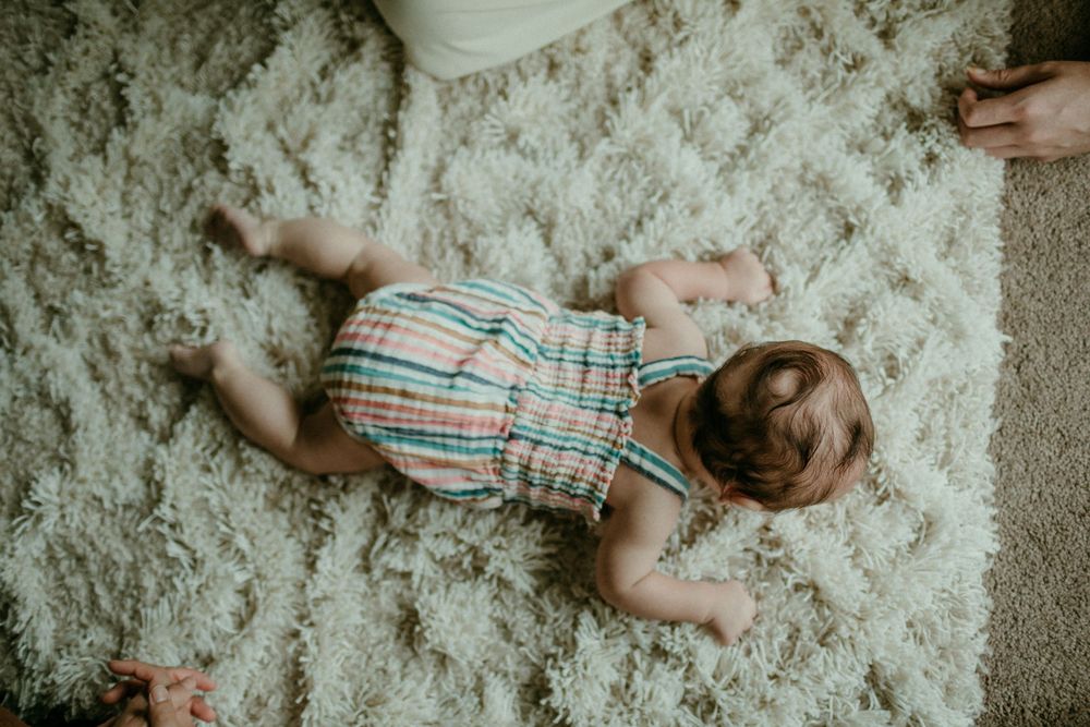 overhead shot of baby scooting on floor in home baby session portland oregon newborn photographer