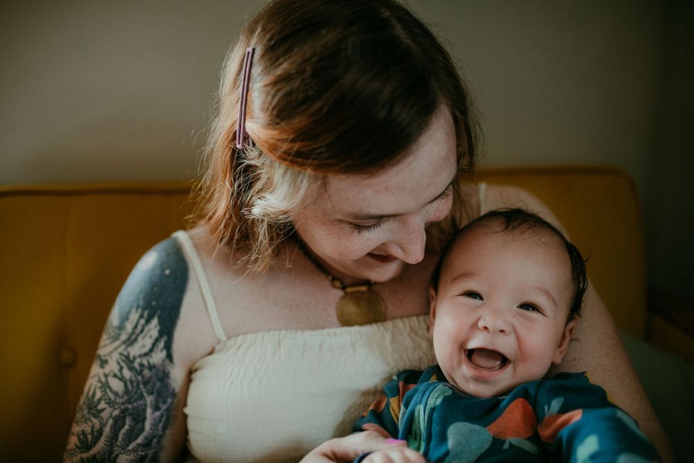 baby laughs with mother in home newborn session portland oregon