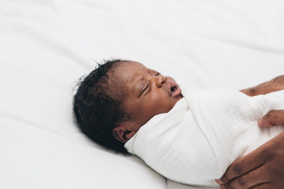 a closeup of a black newborn boy against a white backdrop photographer by NY Family Photographer Paula Brearley NYC newborn photographer