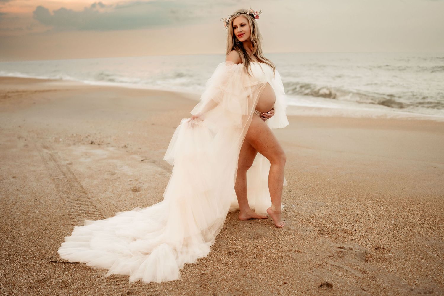 Pregnant woman wearing a flowing dress, embracing her baby bump during a serene maternity photoshoot.