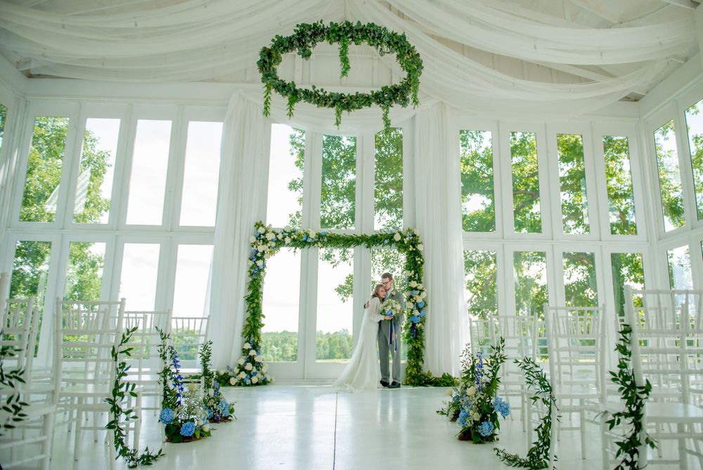White wedding venue interior decorated with hanging greenery garlands and white draping.