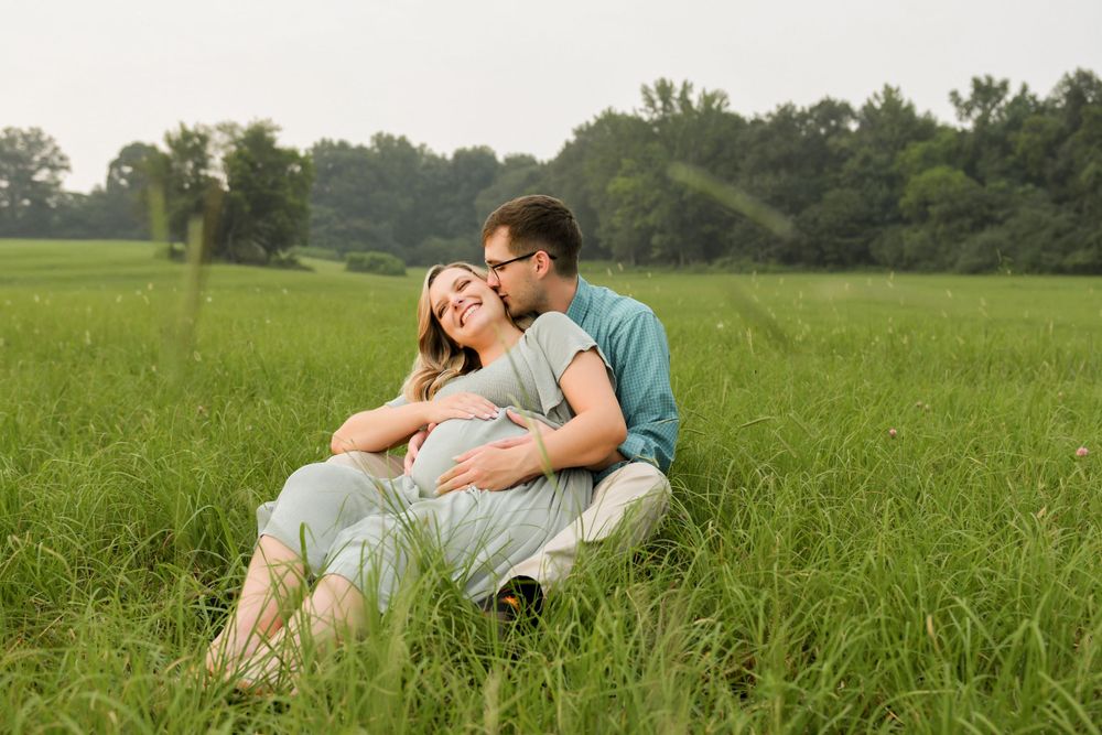 Couple relaxing together in green grass field on sunny day.