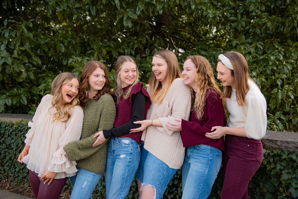 Group of friends in casual attire laugh together outdoors.