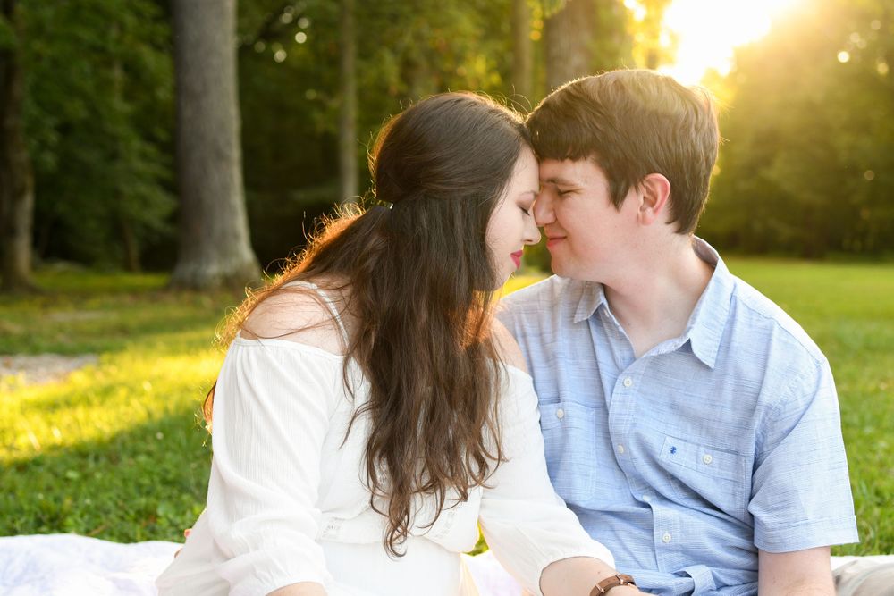 Romantic couple sharing intimate moments at sunset in a grassy park.