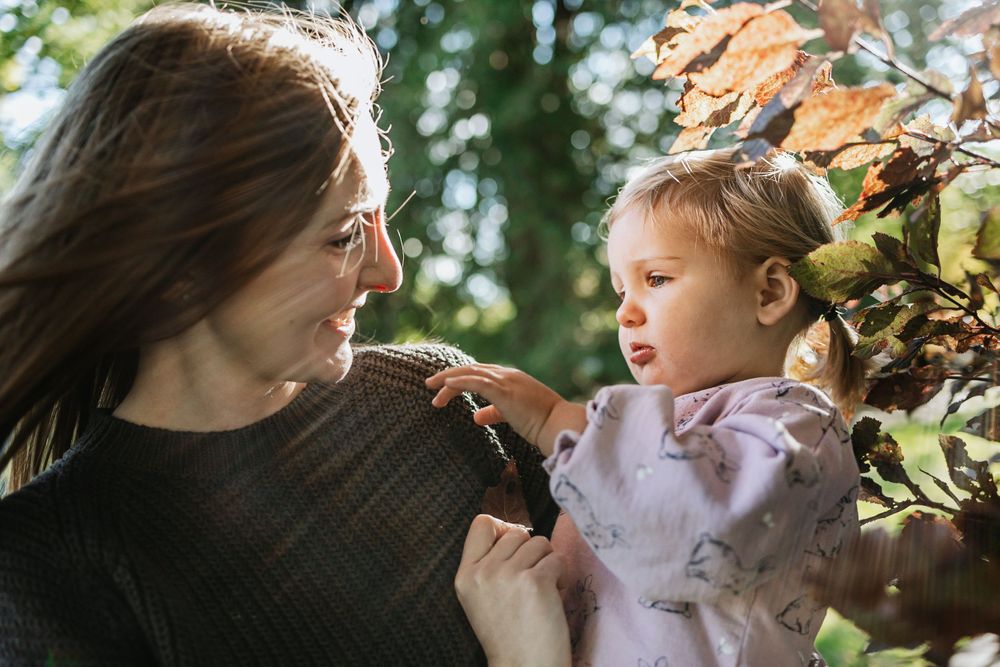 Tender moment captured between two people among autumn leaves and sunlight.