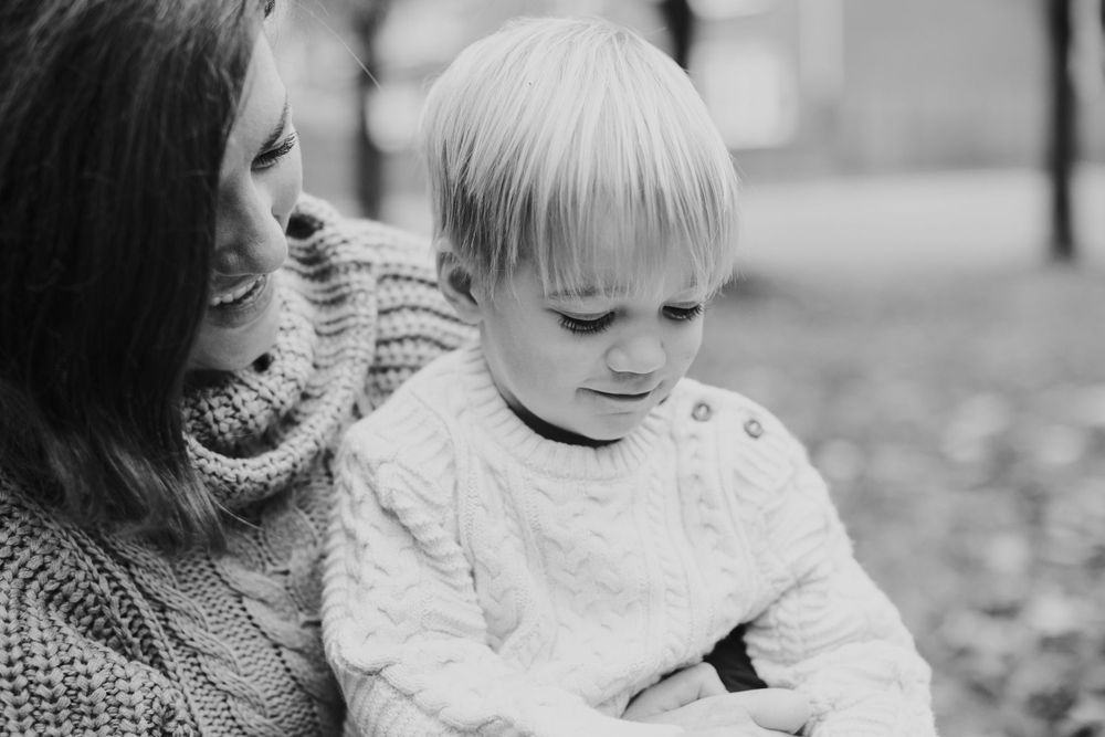 Black and white portrait of tender moment between parent and child in knit sweaters.