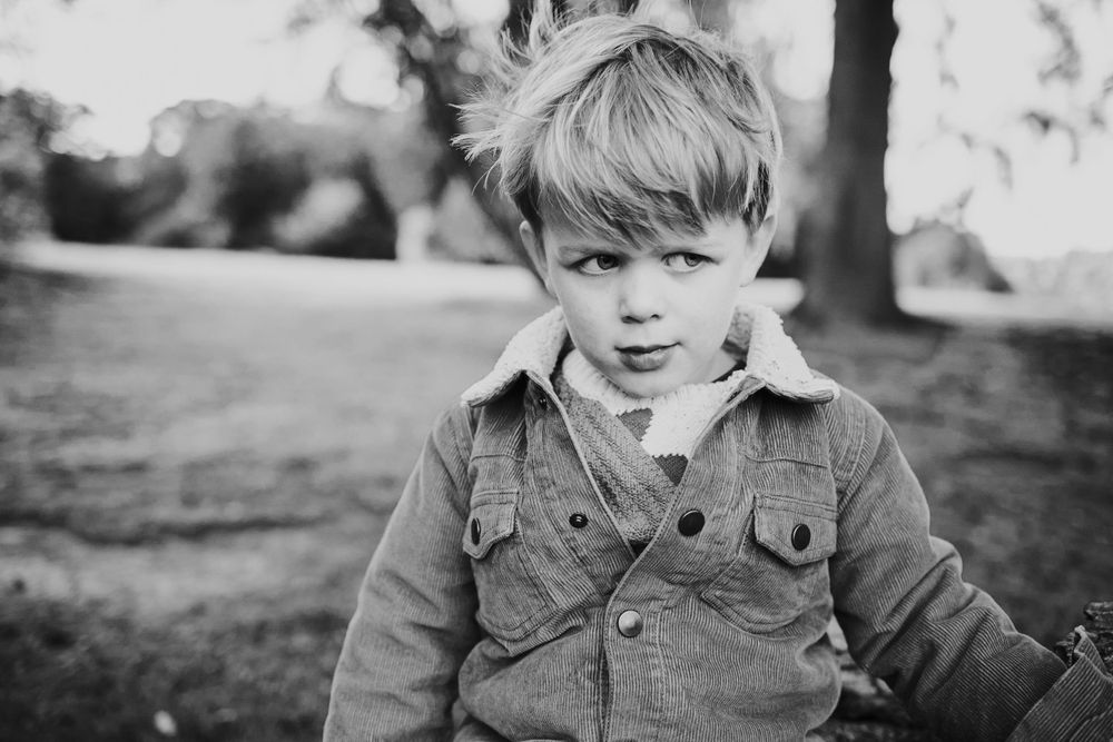 Black and white portrait of a child wearing a denim jacket outdoors.
